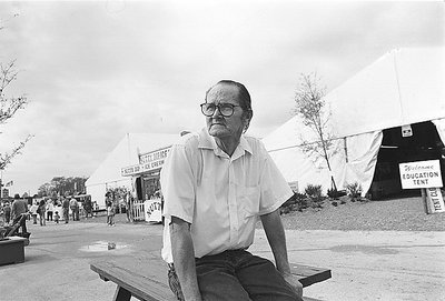 man pondering in front of education tent