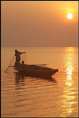 a boat a sunrise and a fisherman